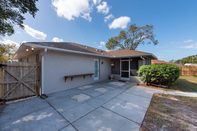 rear view of property featuring a sunroom and a patio area