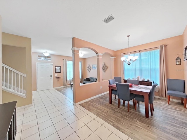 dining room featuring ornate columns, light hardwood / wood-style flooring, and a notable chandelier