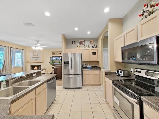 kitchen with light tile patterned flooring, sink, appliances with stainless steel finishes, ceiling fan, and a fireplace