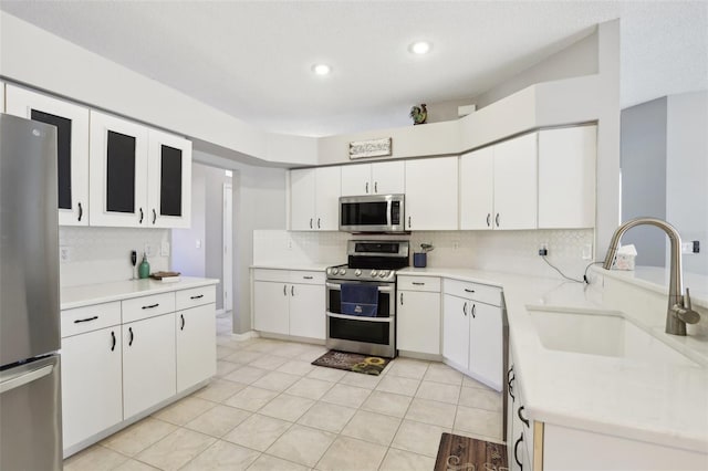 kitchen with white cabinets, appliances with stainless steel finishes, light tile patterned floors, and sink