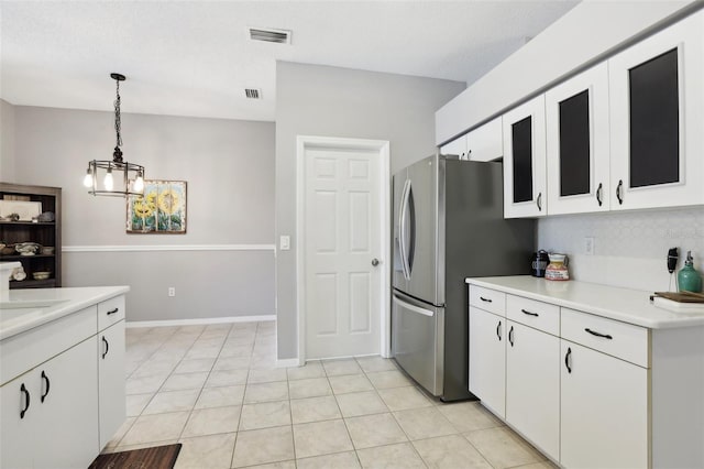 kitchen featuring white cabinets, decorative light fixtures, stainless steel refrigerator, and a notable chandelier