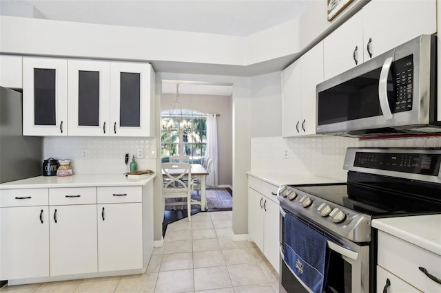 kitchen featuring appliances with stainless steel finishes, white cabinetry, a notable chandelier, and light tile patterned flooring