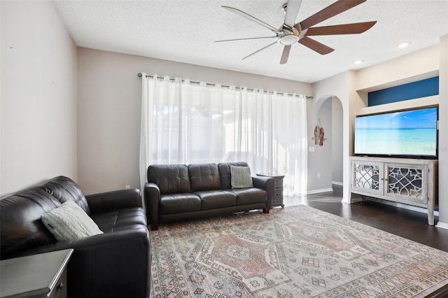 living room featuring ceiling fan, dark hardwood / wood-style flooring, and a textured ceiling