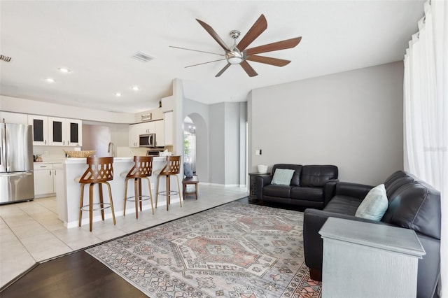 living room with ceiling fan, sink, and light tile patterned flooring