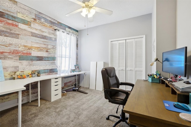 office space with wooden walls, ceiling fan, and light carpet