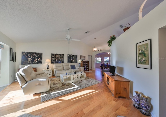 living room with light hardwood / wood-style floors, lofted ceiling, a textured ceiling, and ceiling fan