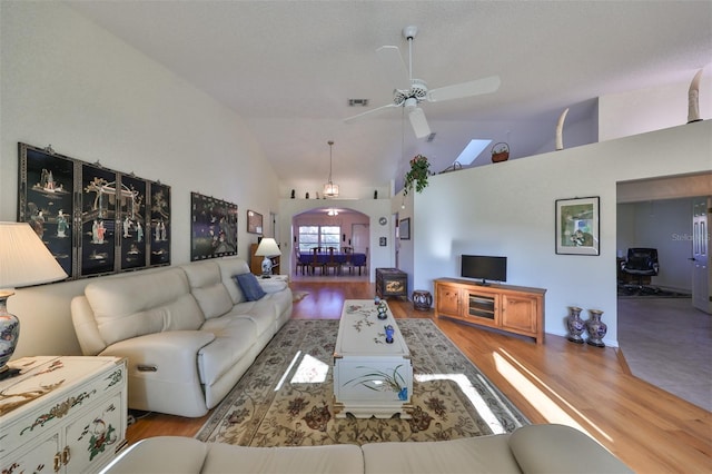 living room with light hardwood / wood-style floors, high vaulted ceiling, and ceiling fan