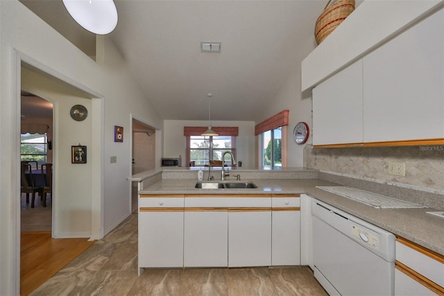 kitchen with white dishwasher, vaulted ceiling, kitchen peninsula, and white cabinets