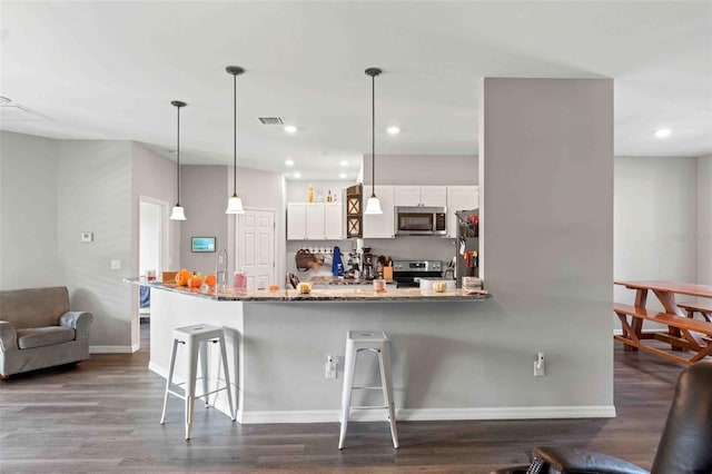 kitchen with kitchen peninsula, a kitchen breakfast bar, white cabinetry, appliances with stainless steel finishes, and decorative light fixtures