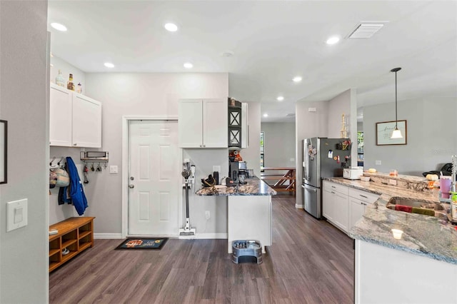 kitchen with white cabinets, dark hardwood / wood-style floors, pendant lighting, and stainless steel fridge