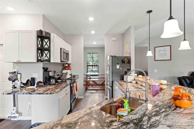 kitchen featuring white cabinets, dark stone counters, decorative light fixtures, and appliances with stainless steel finishes