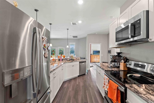 kitchen featuring stainless steel appliances, white cabinetry, pendant lighting, light stone countertops, and dark wood-type flooring