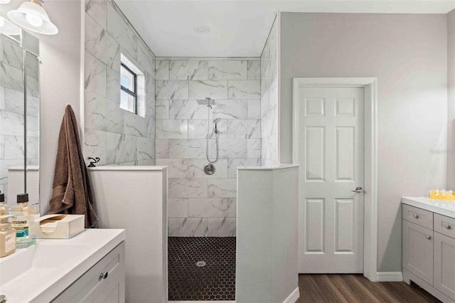 bathroom featuring wood-type flooring, vanity, and a tile shower