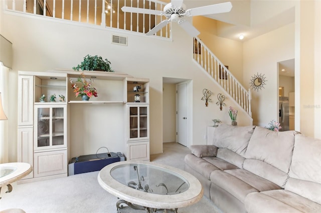 living room featuring ceiling fan, carpet floors, and a towering ceiling