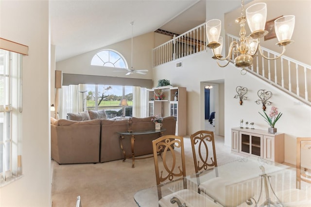 carpeted dining space featuring high vaulted ceiling and ceiling fan with notable chandelier