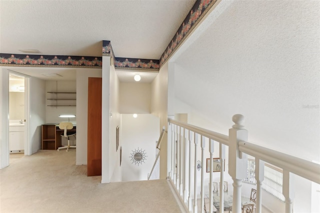 corridor featuring a textured ceiling and carpet