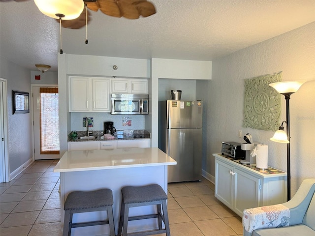 kitchen featuring white cabinets, a breakfast bar area, a kitchen island, pendant lighting, and appliances with stainless steel finishes