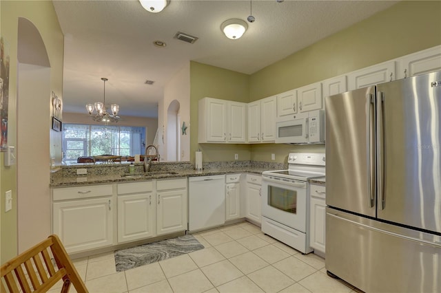 kitchen featuring sink, an inviting chandelier, white cabinets, light stone counters, and white appliances