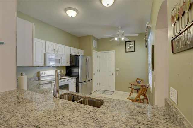 kitchen featuring white cabinets, ceiling fan, light stone countertops, and white appliances