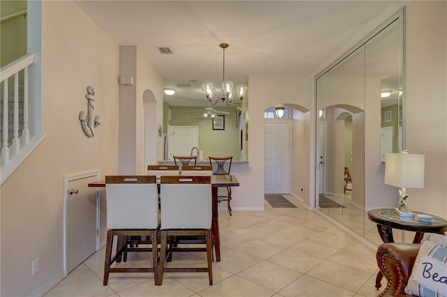 dining area with ceiling fan with notable chandelier and light tile patterned floors