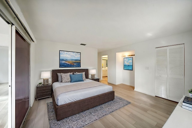 bedroom with ensuite bath and light wood-type flooring