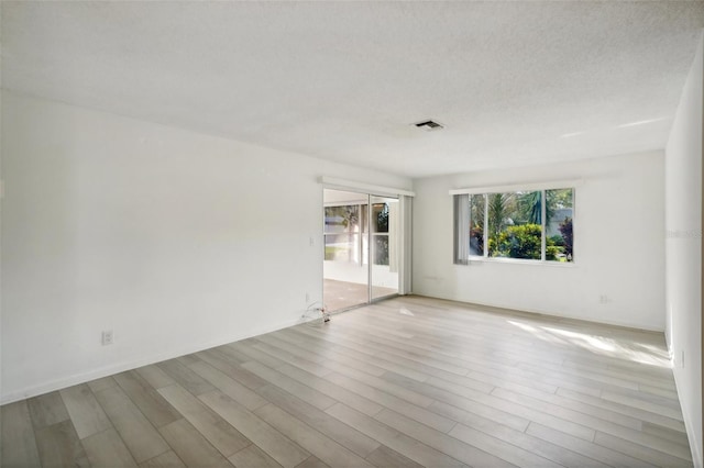 unfurnished room with a textured ceiling and light hardwood / wood-style floors