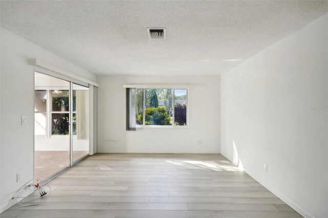 unfurnished room with light hardwood / wood-style floors and a textured ceiling