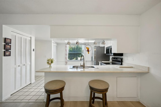 kitchen featuring sink, appliances with stainless steel finishes, a breakfast bar, and kitchen peninsula