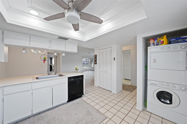 kitchen with black dishwasher, a raised ceiling, light tile patterned floors, white cabinetry, and stacked washer and dryer