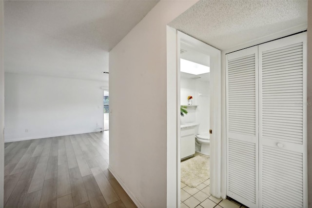 corridor with light hardwood / wood-style floors and a textured ceiling