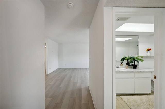 hallway featuring sink and light wood-type flooring