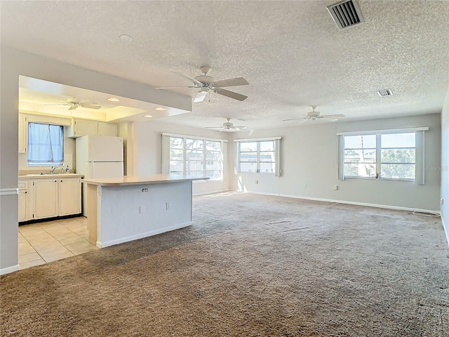 kitchen featuring a textured ceiling, white cabinets, light colored carpet, and white refrigerator