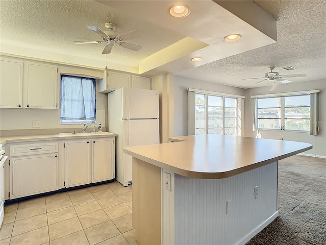 kitchen with a textured ceiling, sink, light colored carpet, a center island, and white refrigerator