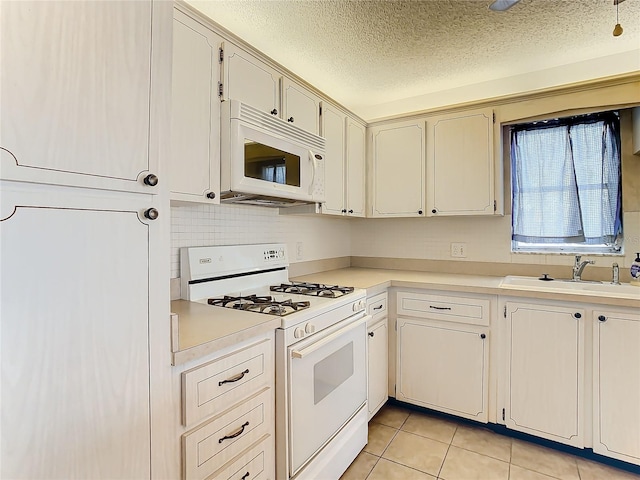 kitchen featuring decorative backsplash, sink, light tile patterned flooring, a textured ceiling, and white appliances