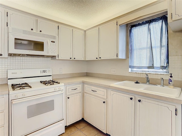 kitchen featuring a textured ceiling, sink, light tile patterned floors, and white appliances