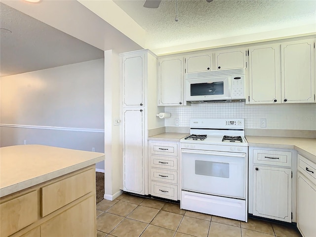 kitchen featuring a textured ceiling, decorative backsplash, light tile patterned flooring, and white appliances