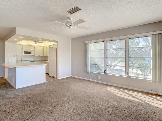 kitchen featuring white cabinets, kitchen peninsula, a textured ceiling, and white appliances