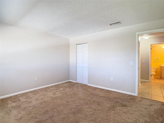 empty room featuring a textured ceiling and carpet flooring