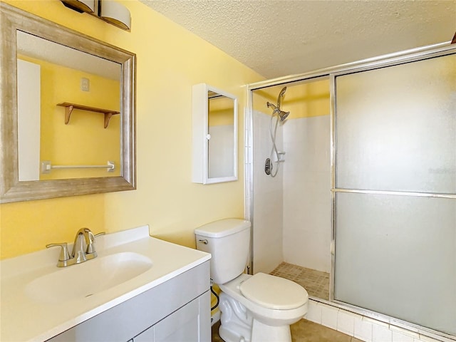 bathroom featuring a shower with door, a textured ceiling, toilet, vanity, and tile patterned flooring