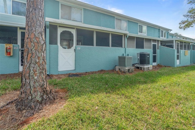 back of property featuring central AC unit, a lawn, and a sunroom