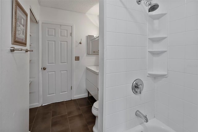 full bathroom featuring tile patterned flooring, tiled shower / bath, a textured ceiling, vanity, and toilet