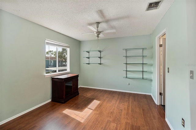 empty room featuring dark hardwood / wood-style flooring, a textured ceiling, and ceiling fan