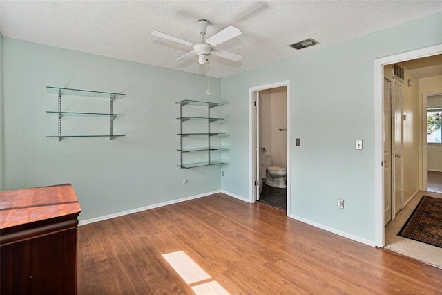 unfurnished bedroom with hardwood / wood-style flooring, ceiling fan, a textured ceiling, and ensuite bathroom