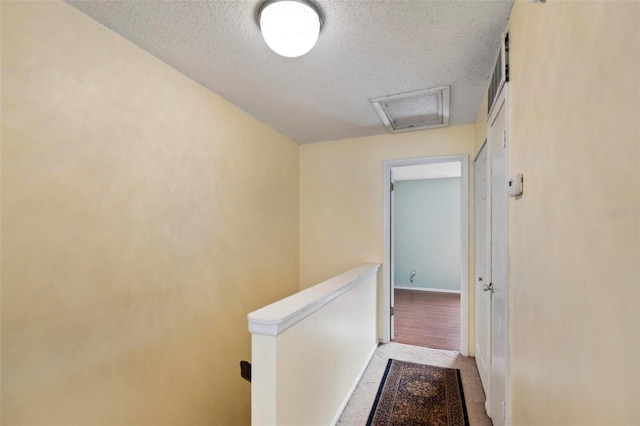 hall with light wood-type flooring and a textured ceiling