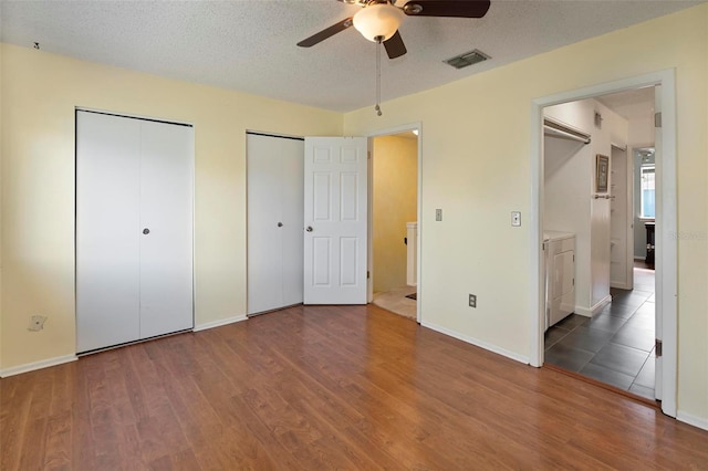 unfurnished bedroom with dark wood-type flooring, a textured ceiling, ceiling fan, and ensuite bath