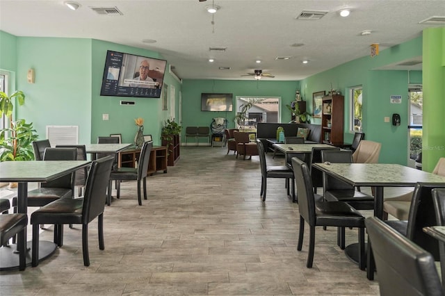 dining area featuring a textured ceiling, light wood-type flooring, and ceiling fan