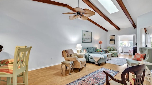 living room featuring beam ceiling, a skylight, ceiling fan, and light hardwood / wood-style floors