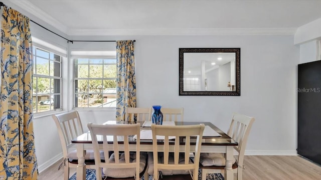 dining room with ornamental molding and light hardwood / wood-style flooring