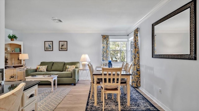 dining room with light wood-type flooring and crown molding