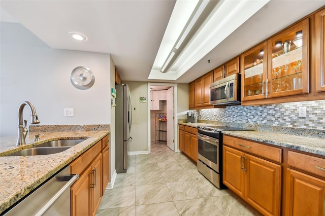 kitchen with stainless steel appliances, sink, light stone counters, and tasteful backsplash